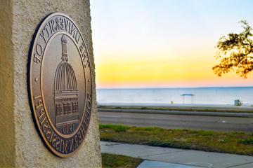 Gulf Park Campus seal in gateway with beach view